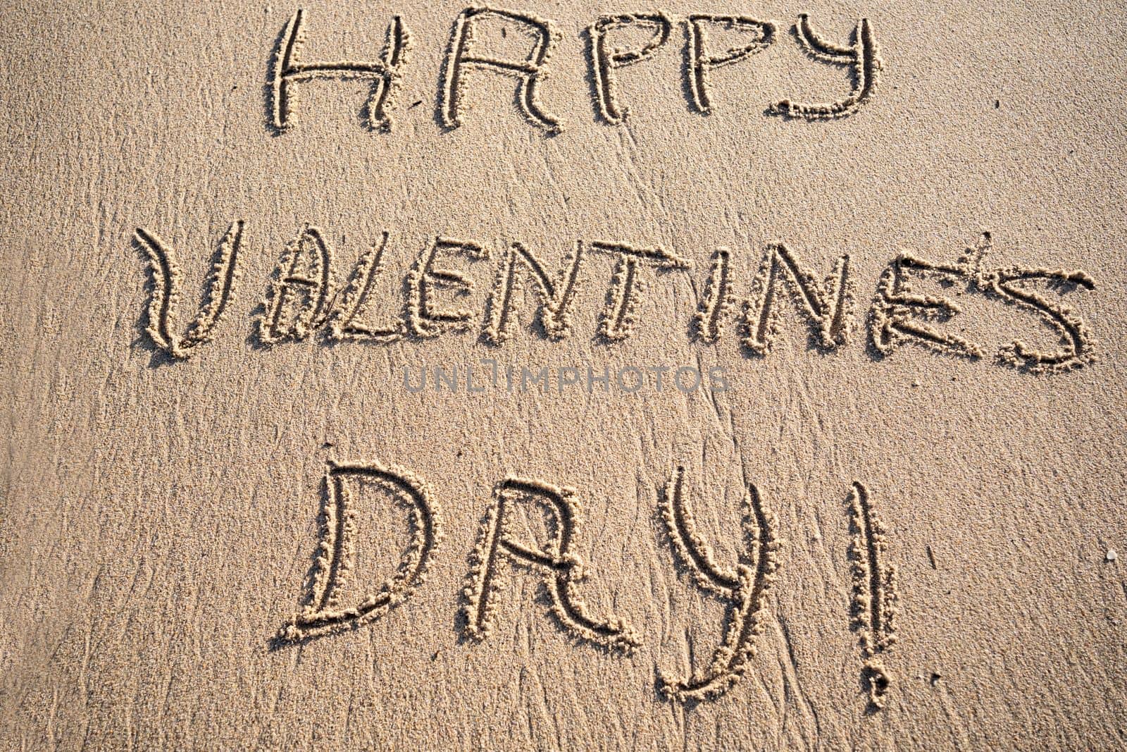Happy Valentine's Day written on the sand of tropical beach.