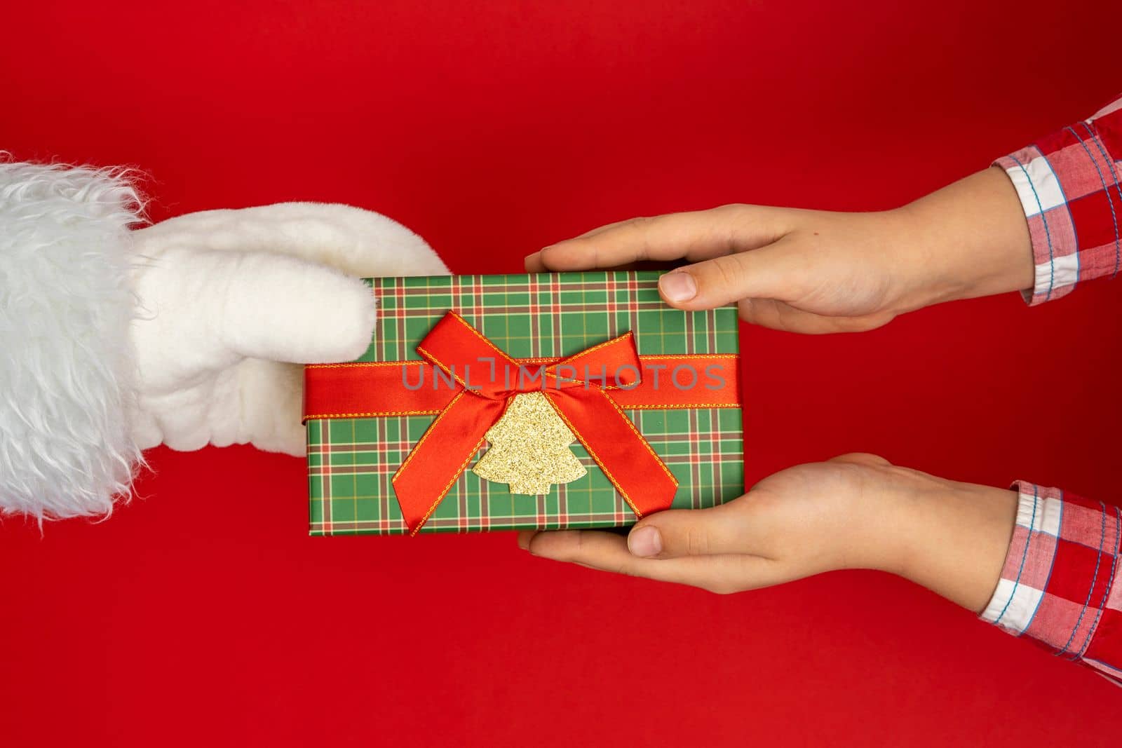 Santa's hands give gifts to children at Christmas. red background with copy space Christmas time