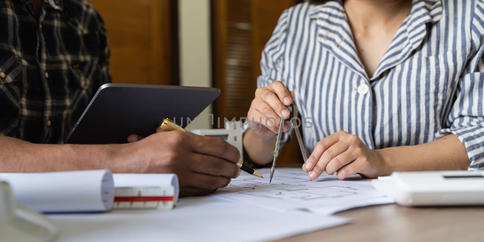 Architect woman working with blueprints for architectural plan, engineer sketching a construction project, green energy concept.