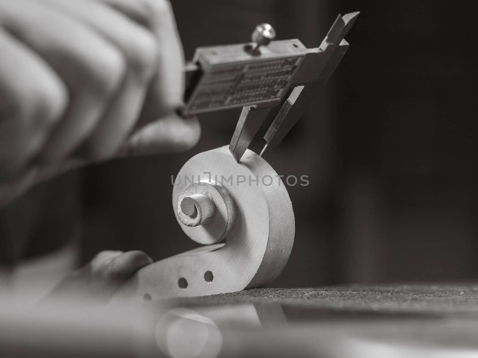 violin maker using a meter to shape and accurate measure fiddle scroll