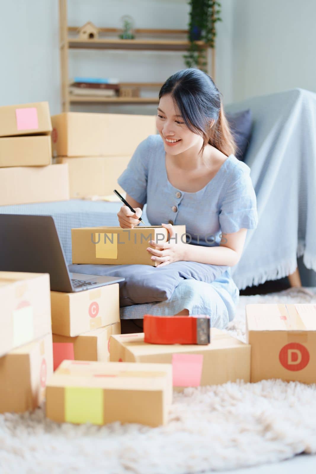 Starting small business entrepreneur of independent young Asian woman online seller is using computer and taking orders to pack products for delivery to customers. SME delivery concept.