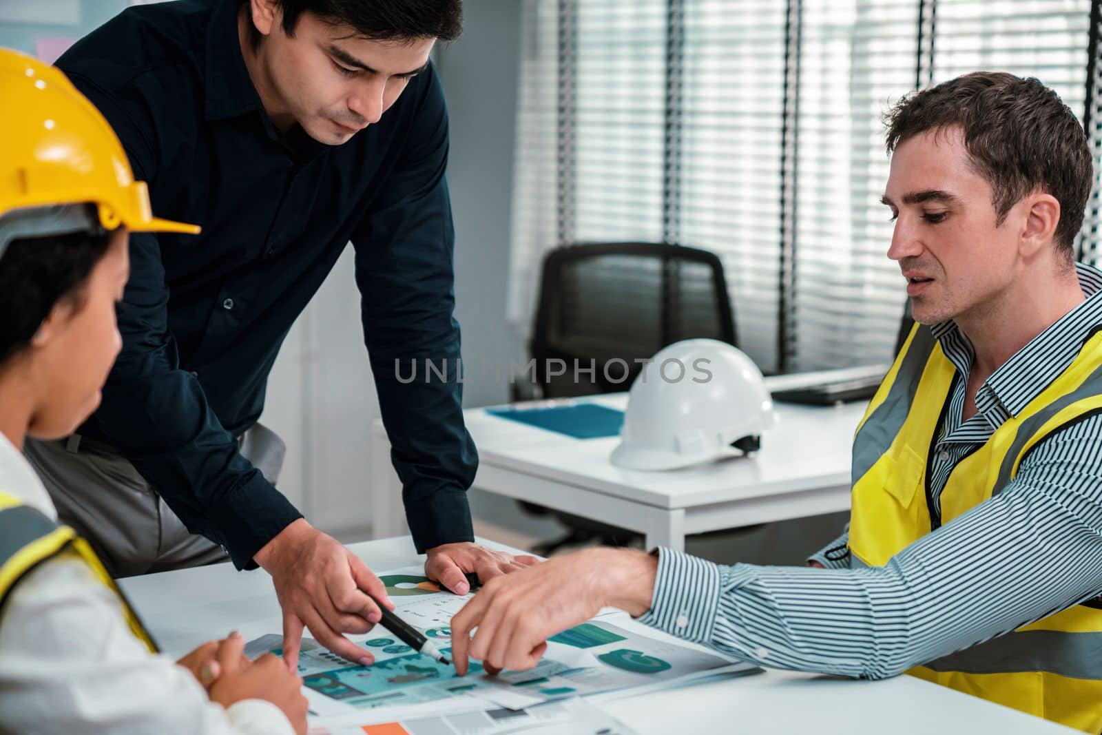 Engineers and competent employer discussing plans and blueprints together with tablet in the office. Concept of team contribution of ideas for engineering project.