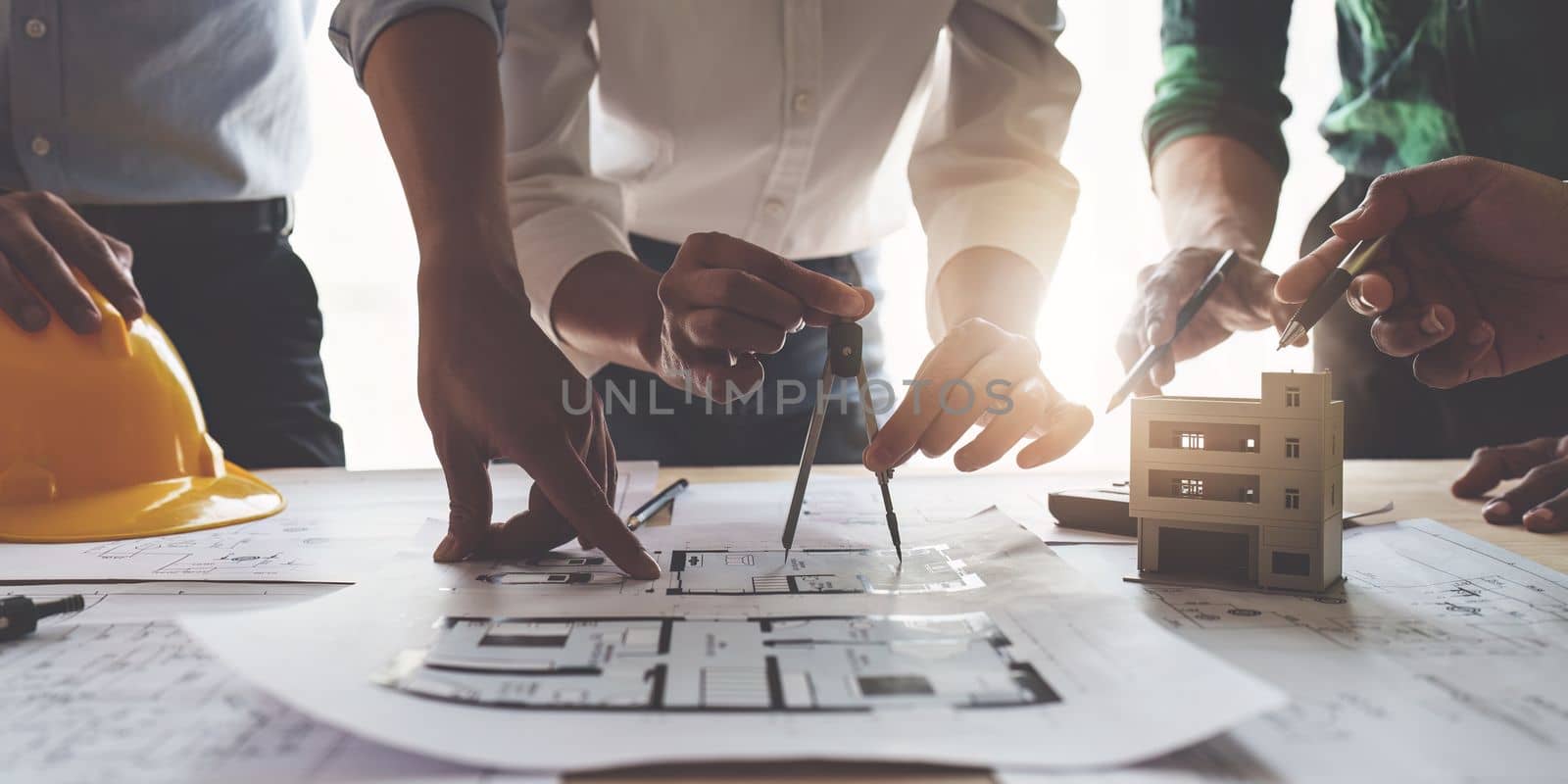 Architect team working with blueprints for architectural plan, engineer sketching a construction project, green energy concept.