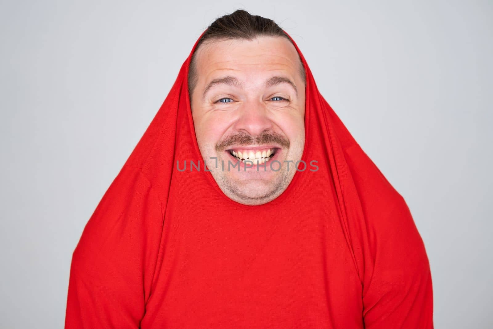 Funny man covering head with sweater smiling cheerful and funny. 