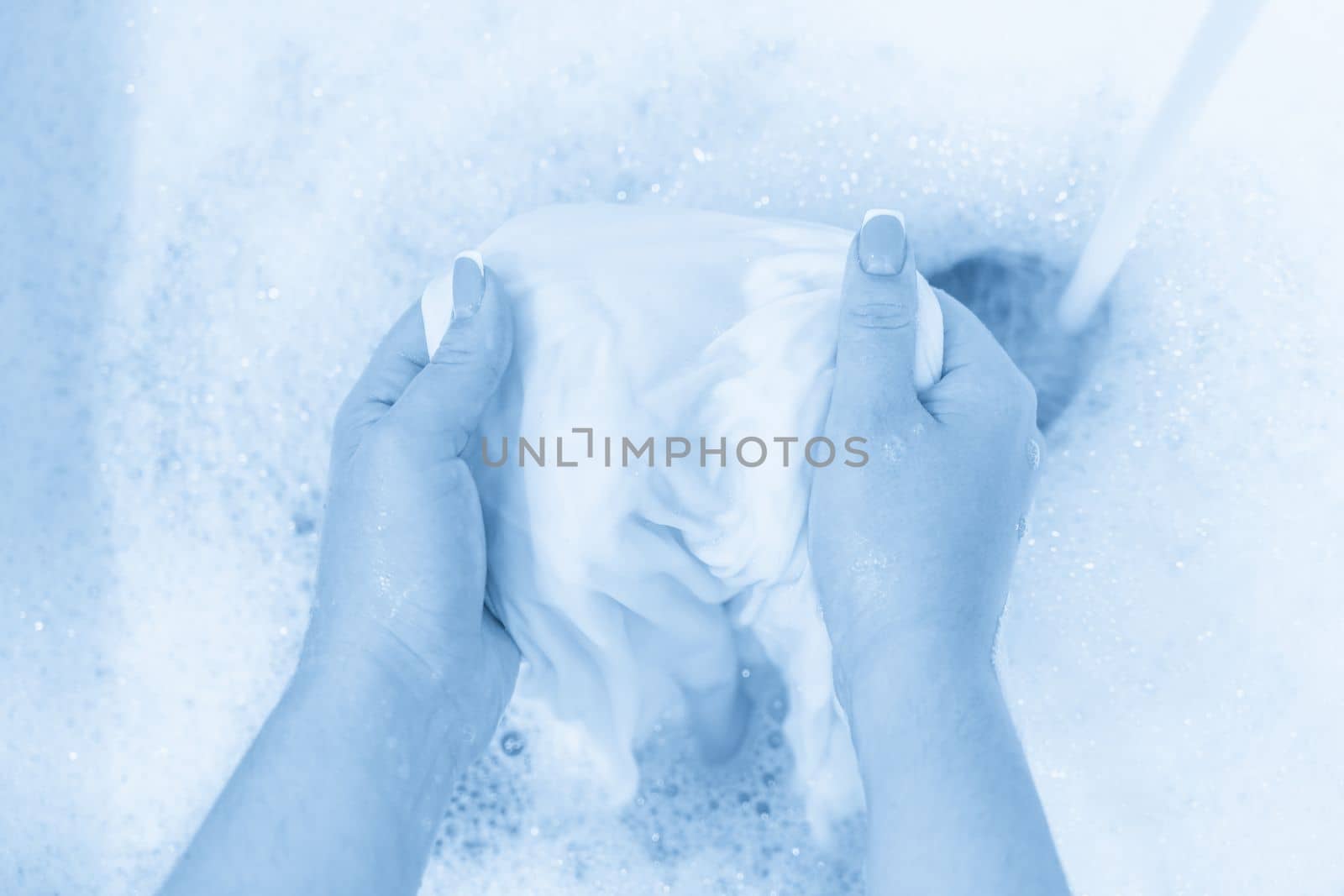 Hand washing white clothes in sink to bleach by Mariakray