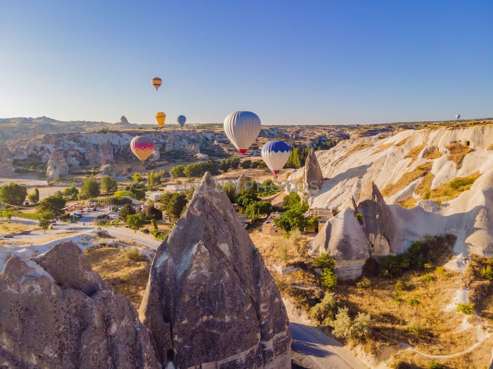 Colorful hot air balloons flying over at fairy chimneys valley in Nevsehir, Goreme, Cappadocia Turkey. Spectacular panoramic drone view of the underground city and ballooning tourism. High quality by galitskaya