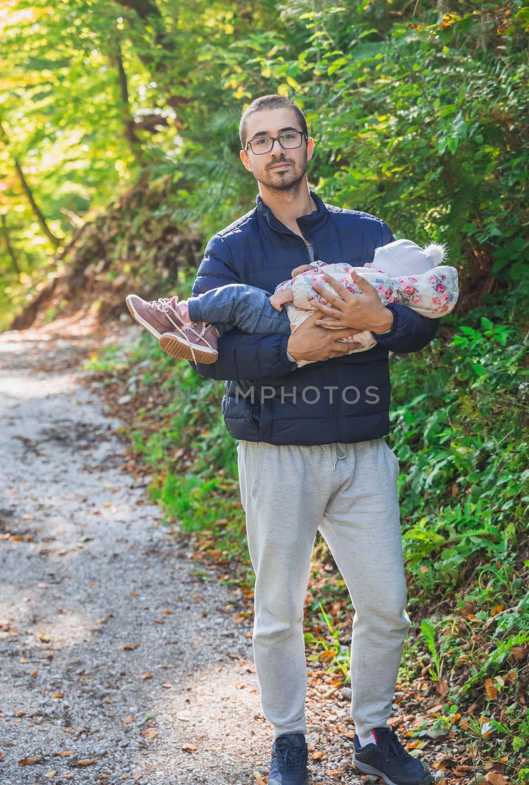 Father holding a sleeping baby in the park.