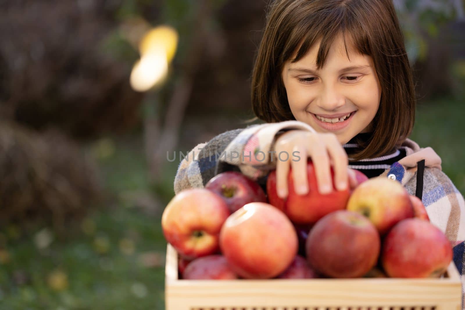 Schoolkid girl's hand take red apple and eats an apple. Female hand choosing organic fruits. Portrait of healthy schoolgirl eating big red apple by uflypro