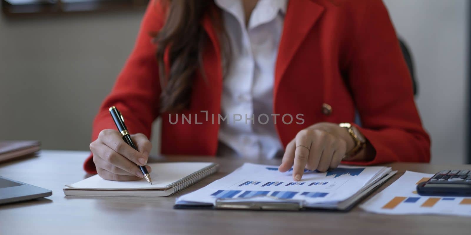 Asian Business woman using calculator and laptop for doing math finance on an office desk, tax, report, accounting, statistics, and analytical research concept..