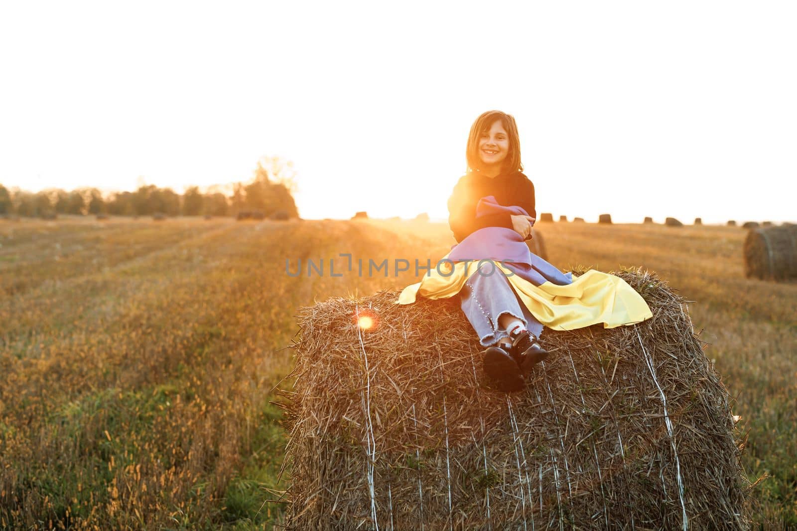 Portrait of child smiles wearing Ukrainian flag blue and yellow flag of Ukraine fluttering on sunset sky background. Flag of Ukraine in hands of happy girl Ukrainian. Flag Day. Constitution day by uflypro