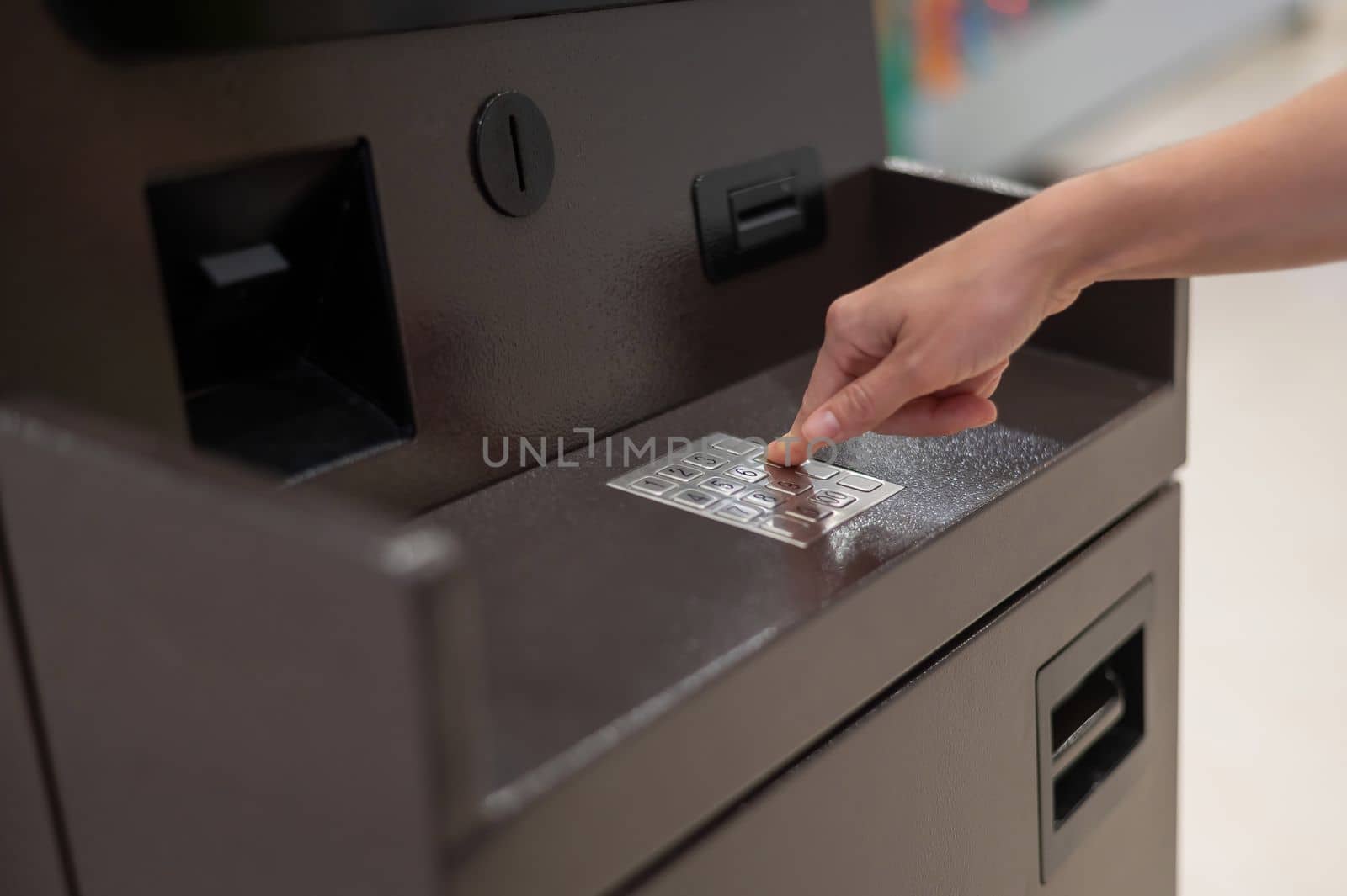 Faceless woman dialing bank card pin at ATM