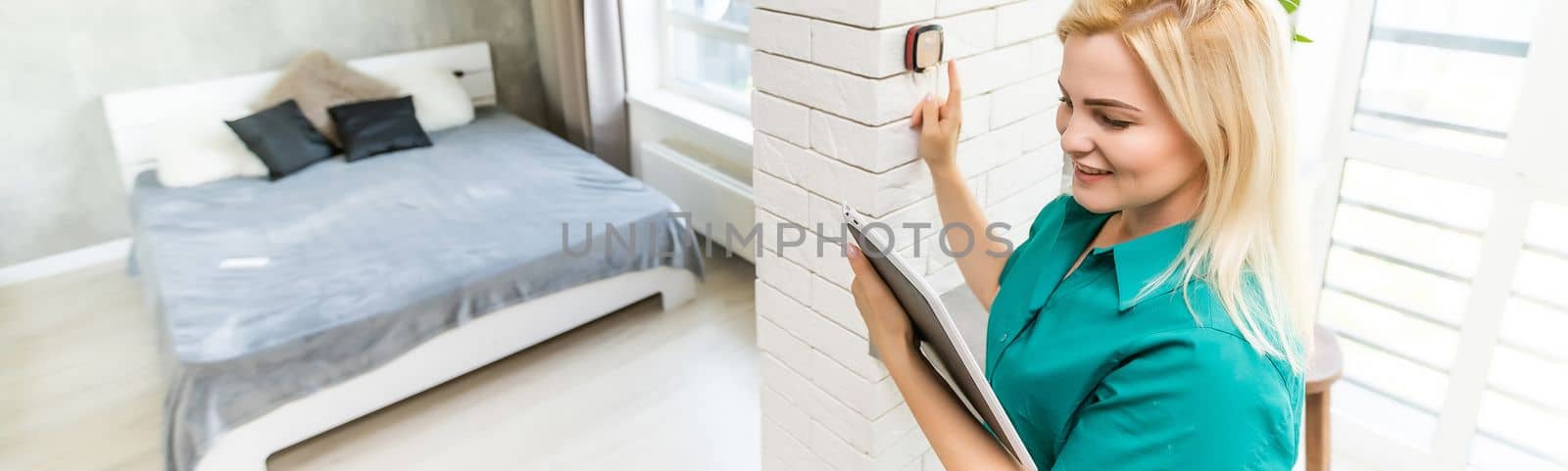 Smiling Woman Adjusting Thermostat On Home Heating System.