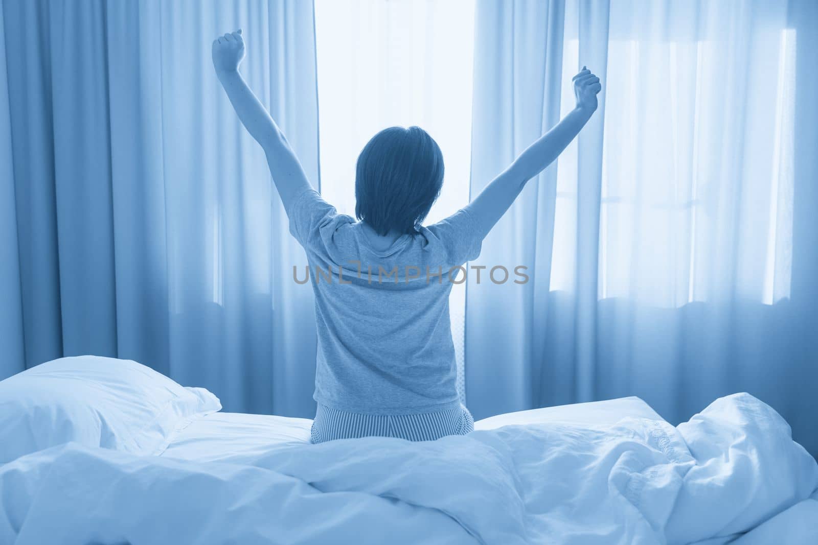 Woman stretching in bed after wake up, soft tone by Mariakray