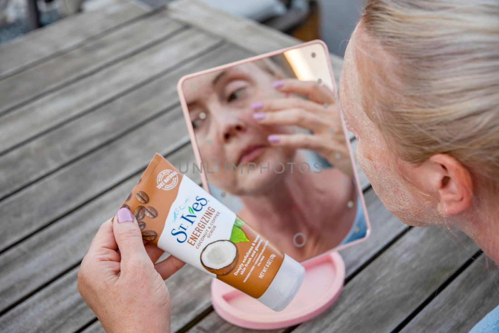 ST. Ives Fresh Energizing Coconut and Coffee Scrub in Tube, reflections in the mirror, a middle-aged woman applies a scrub on her face in front of a mirror, As,Belgium, August 13,2022, High quality photo
