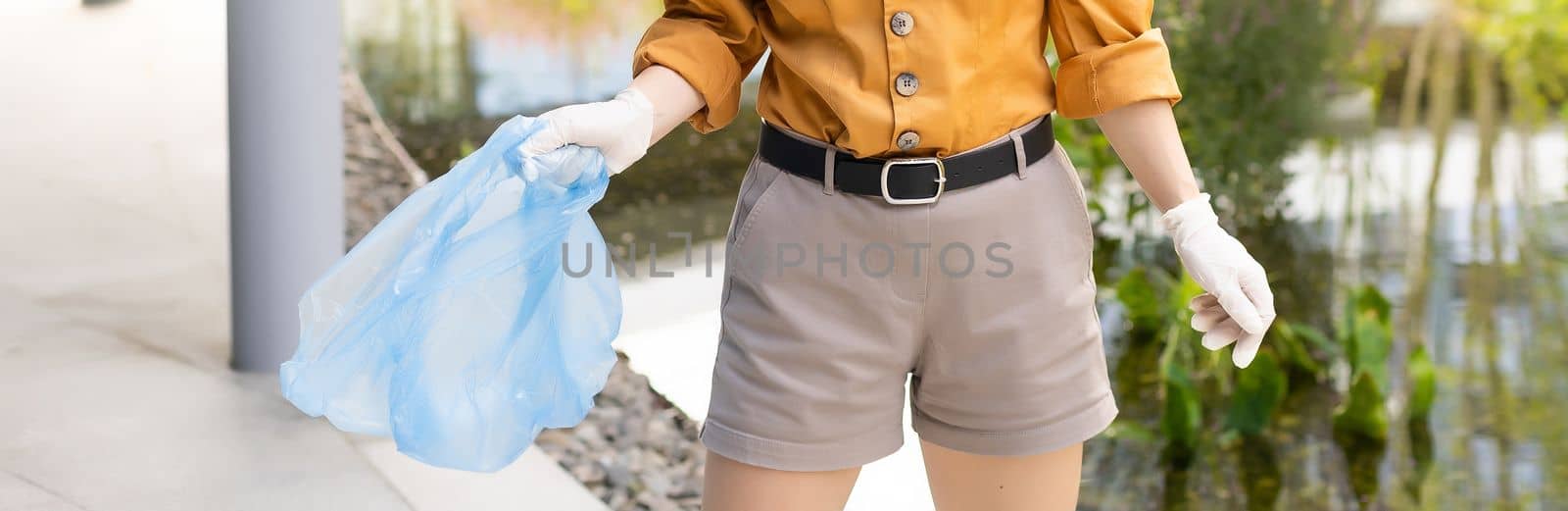 woman picking up plastic household waste in park.