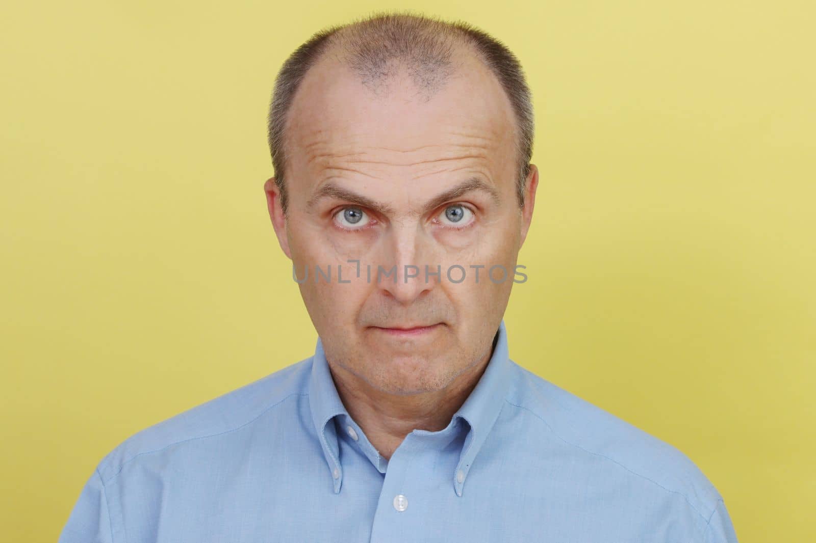 Portrait of a handsome man 45-55 years old in a blue shirt looks at the camera. by gelog67