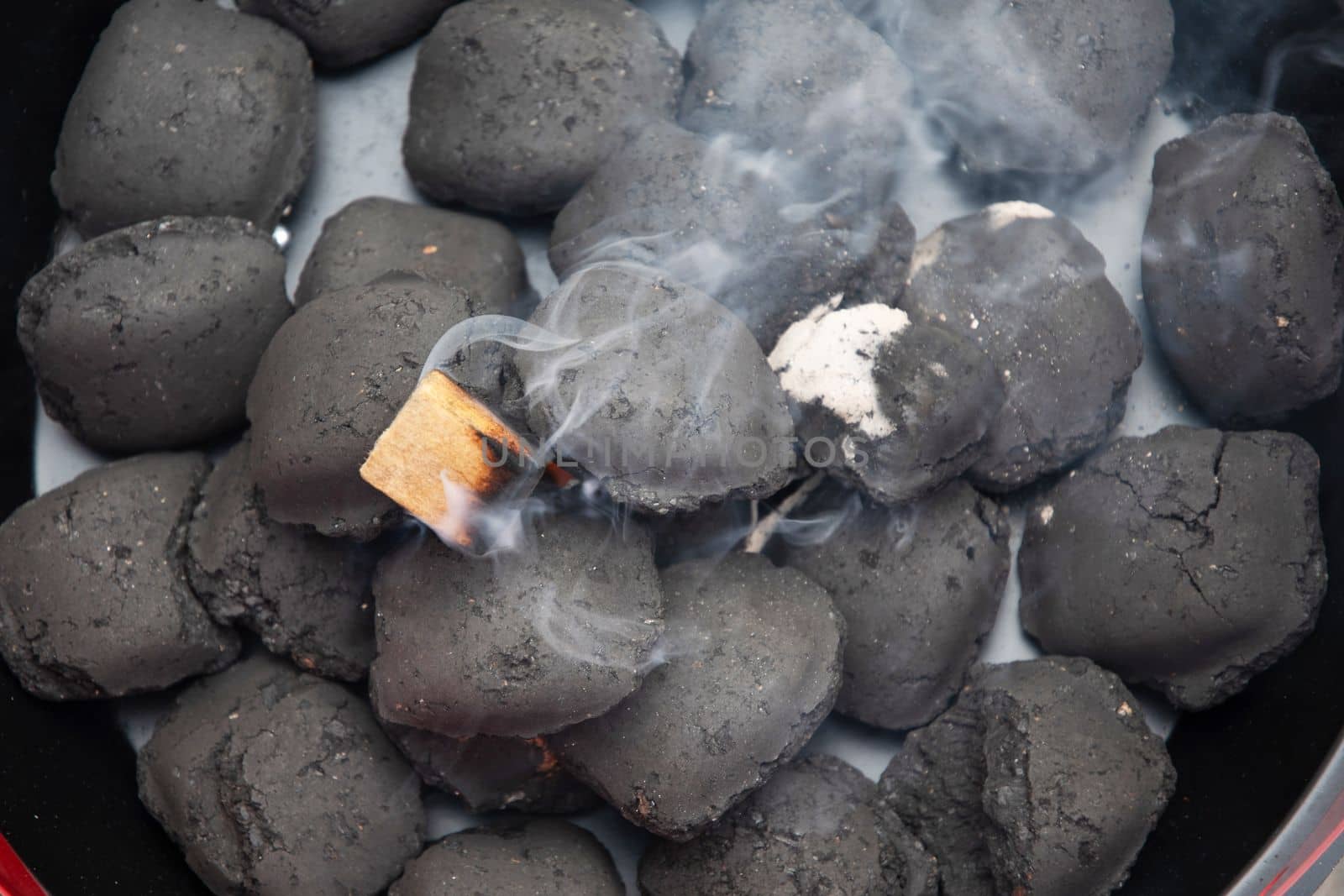 a man lights a fire with a lighter special charcoals for a barbecue  by KaterinaDalemans