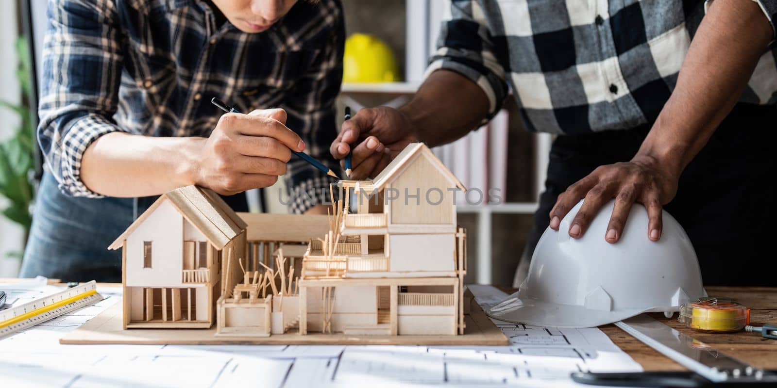 Architect team working with blueprints for architectural plan, engineer sketching a construction project, green energy concept.