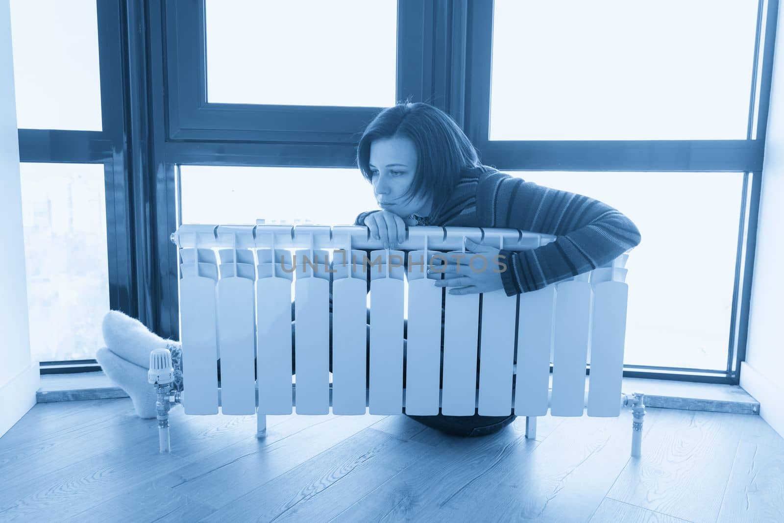 Woman wearing pullover sitting near heater radiator