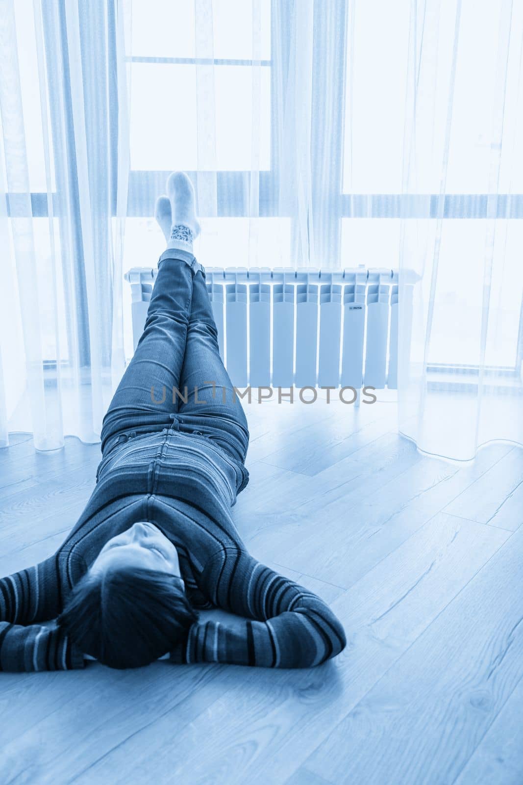 Woman laying on floor with feet raised up on radiator for warming