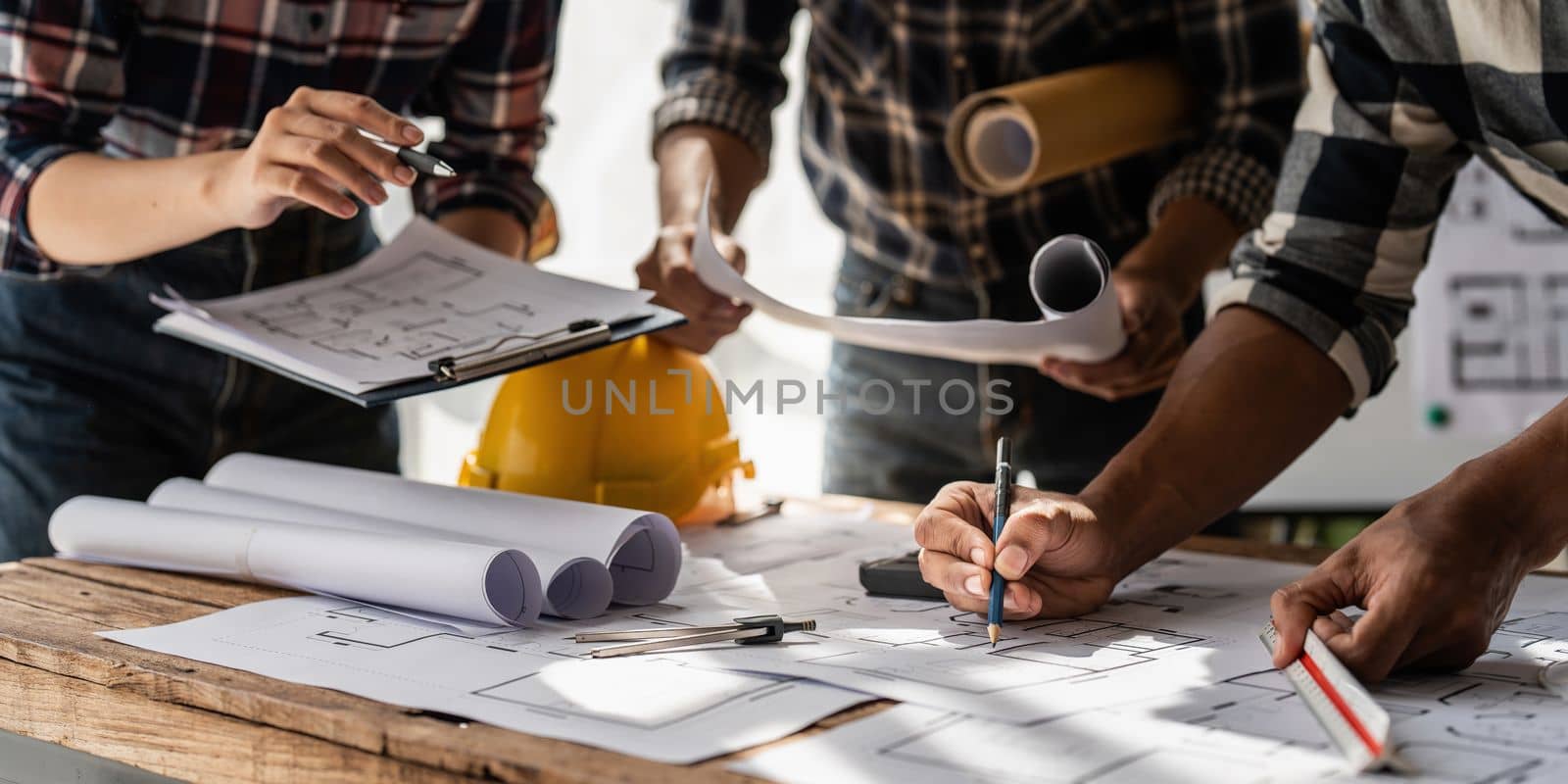 Architect team working with blueprints for architectural plan, engineer sketching a construction project, green energy concept by itchaznong