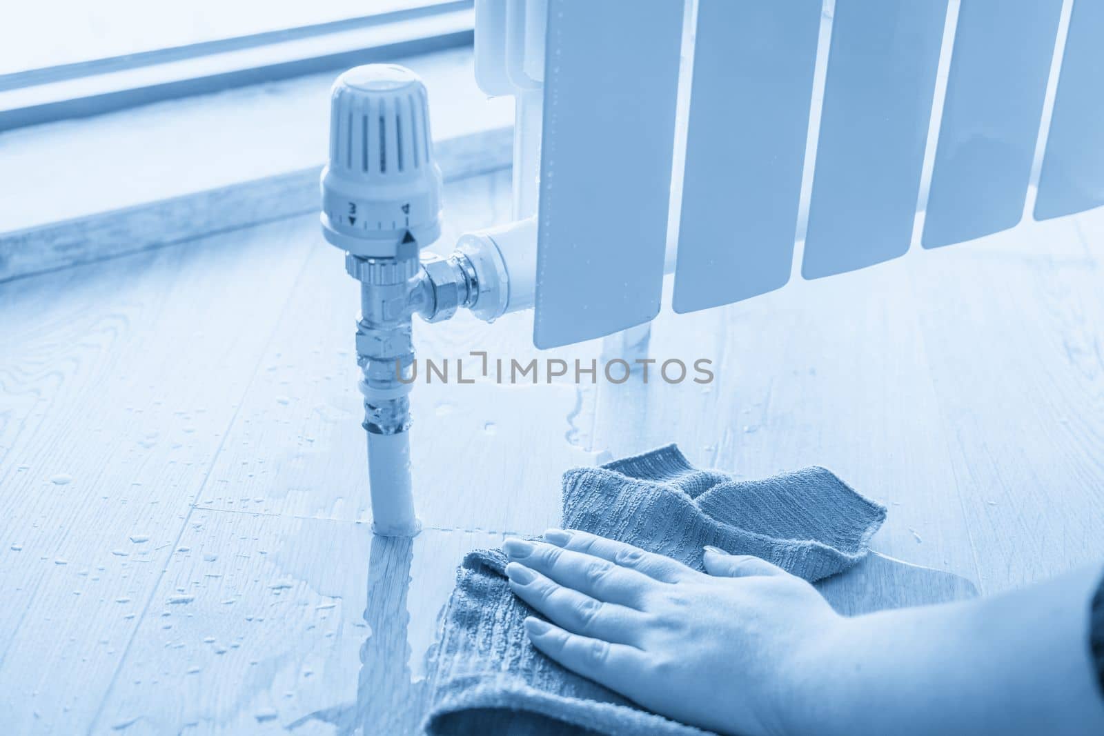 Female hand with rag cleaning water from heating radiator