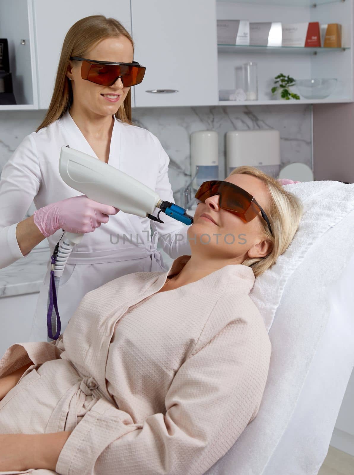 Woman receiving laser treatment in cosmetology clinic by Mariakray