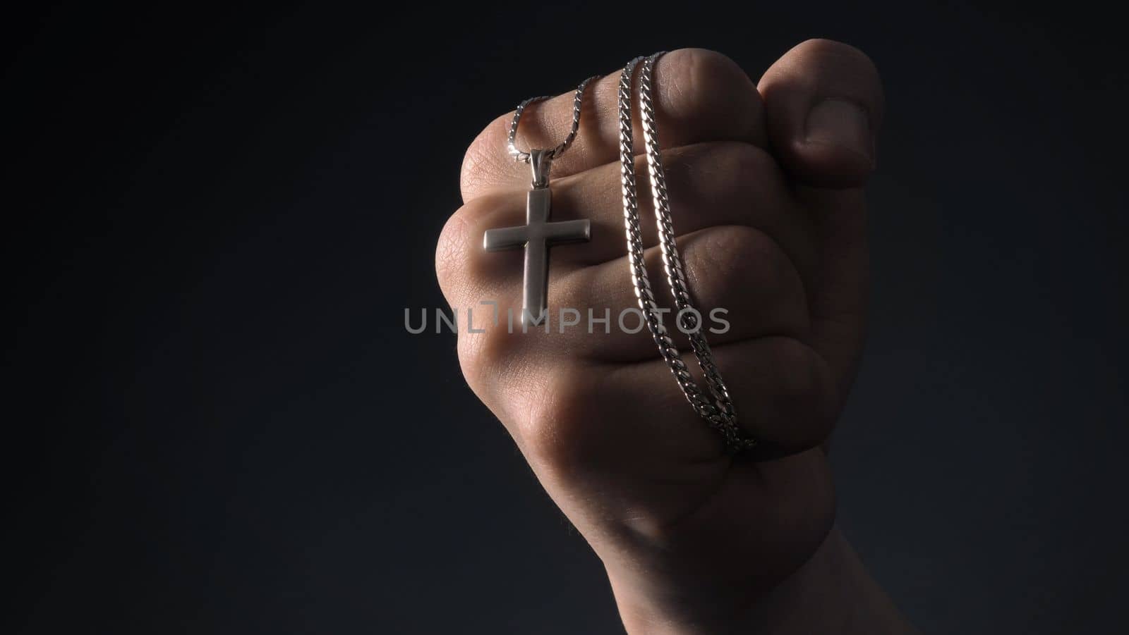 Close-up images of crucifix pendant and necklace in hand  by gnepphoto