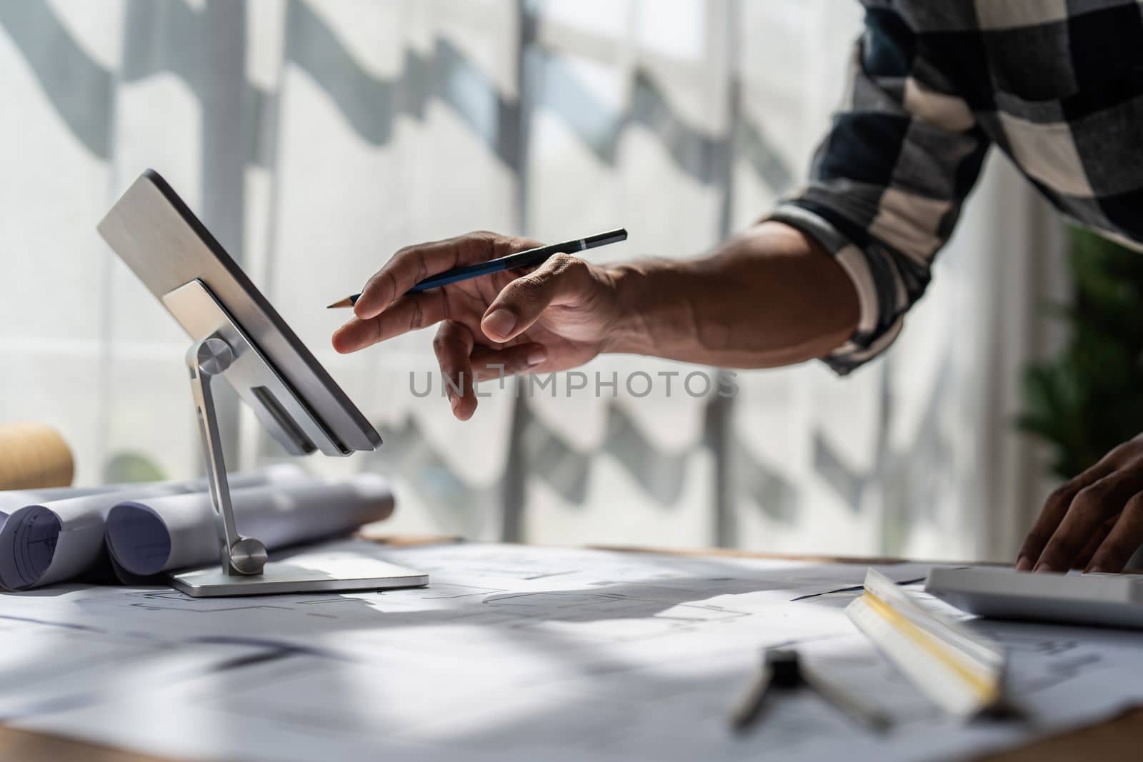 Architect man working with blueprints for architectural plan, engineer sketching a construction project, green energy concept.