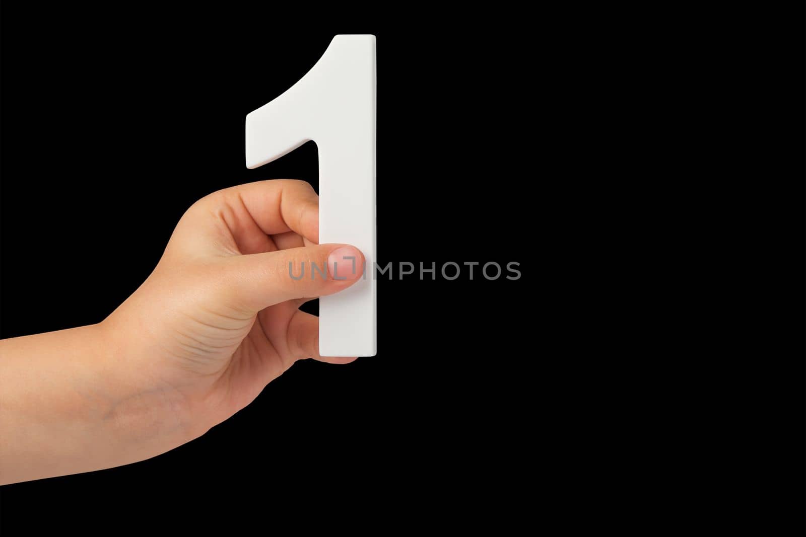 Number one in a hand isolated on a black background. Number one white in a child's hand on a black background