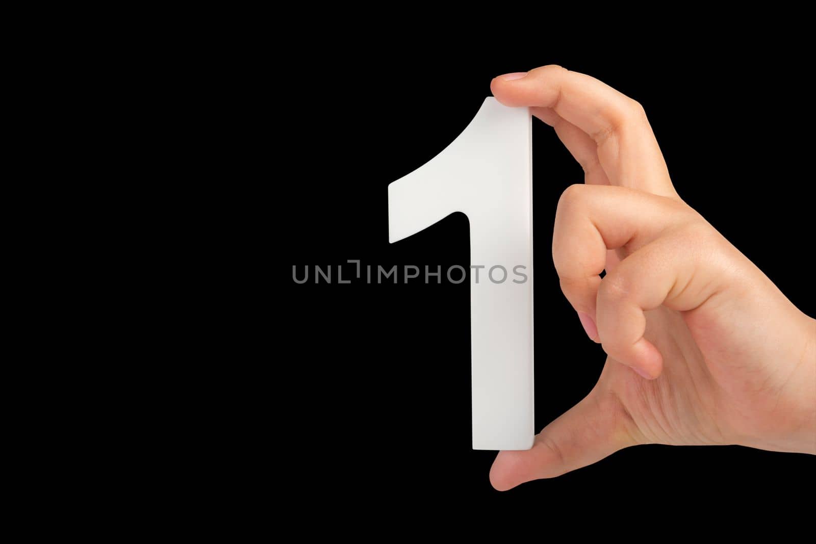 Number one in a hand isolated on a black background. Number one white in a child's hand on a black background