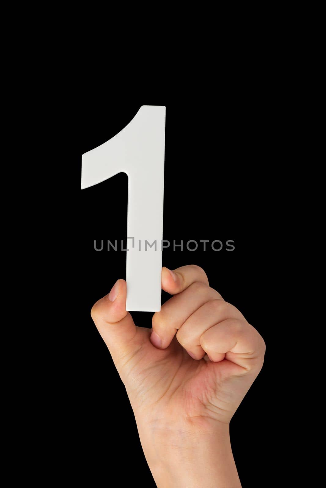 Number one in a hand isolated on a black background. Number one white in a child's hand on a black background