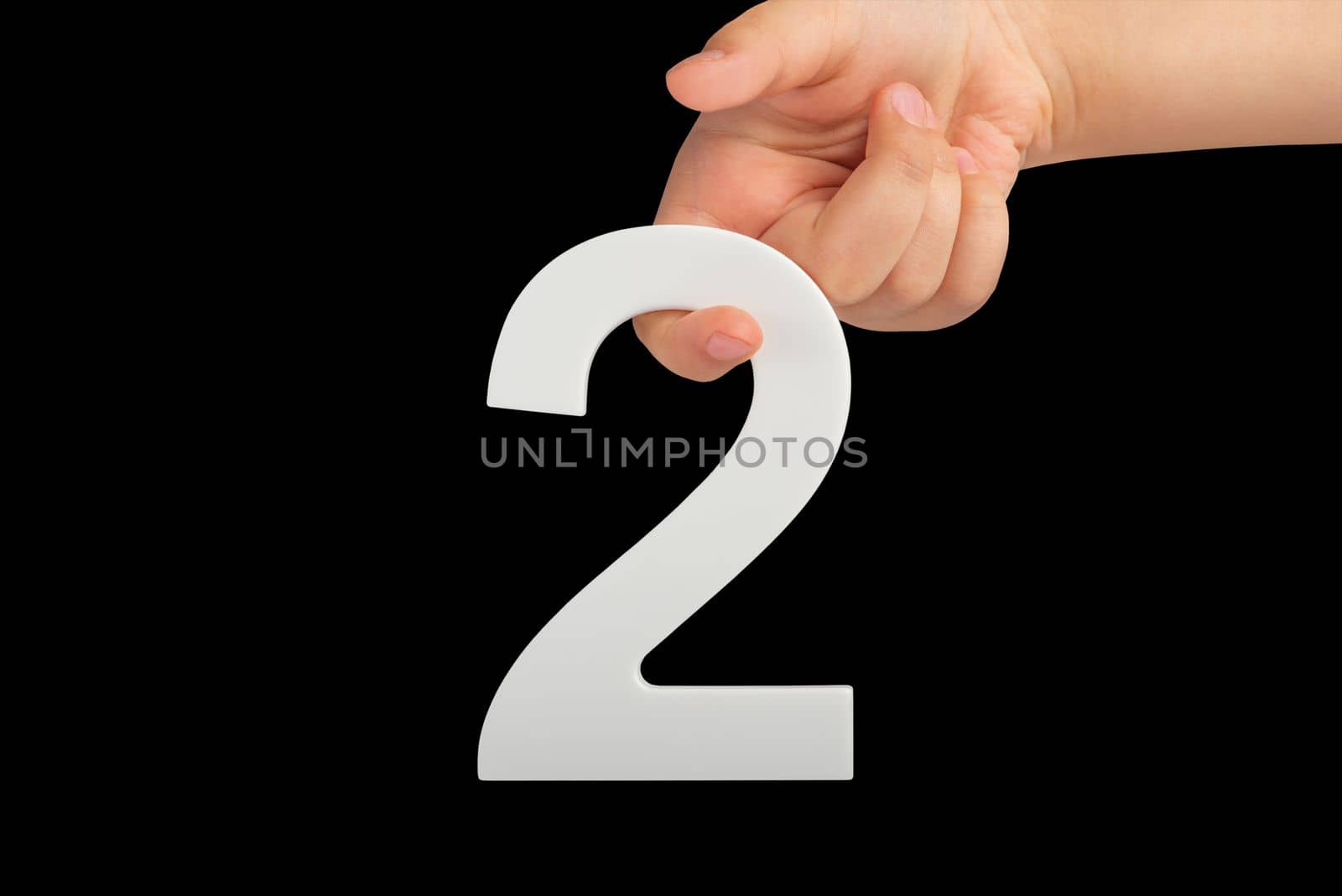 number two in hand isolated on black background. Number two white in a child's hand on a black background. For inserting into a project or design. by SERSOL