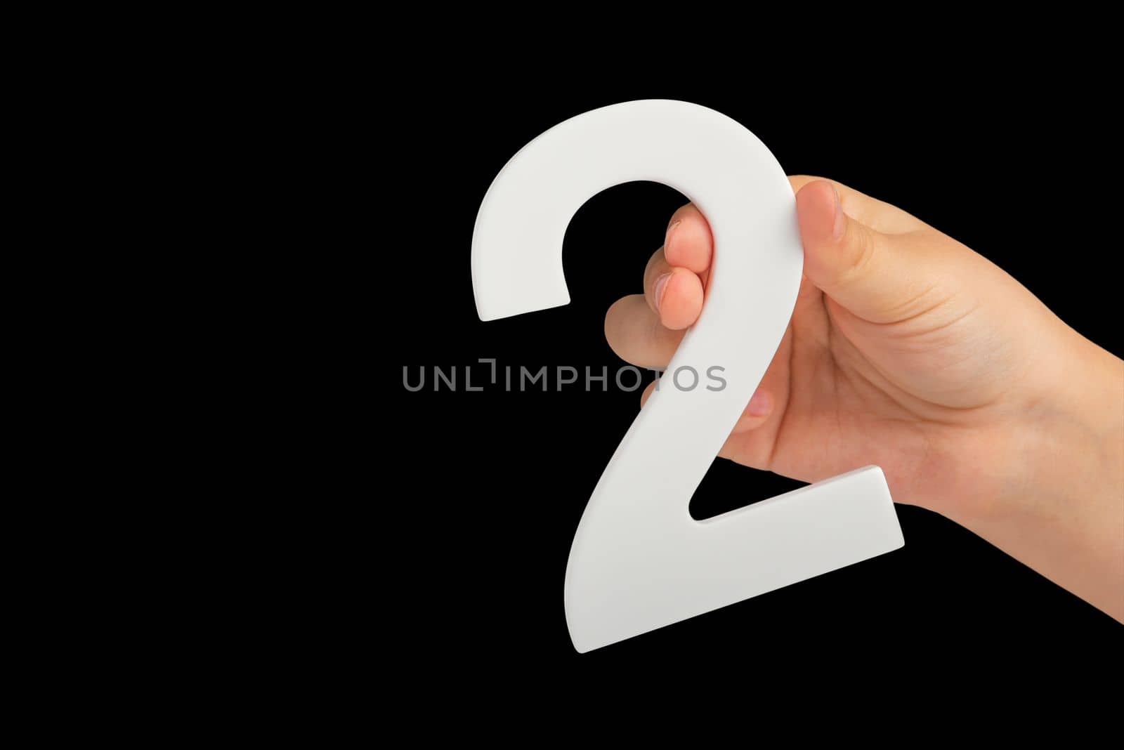 number two in hand isolated on black background. Number two white in a child's hand on a black background. For inserting into a project or design. by SERSOL