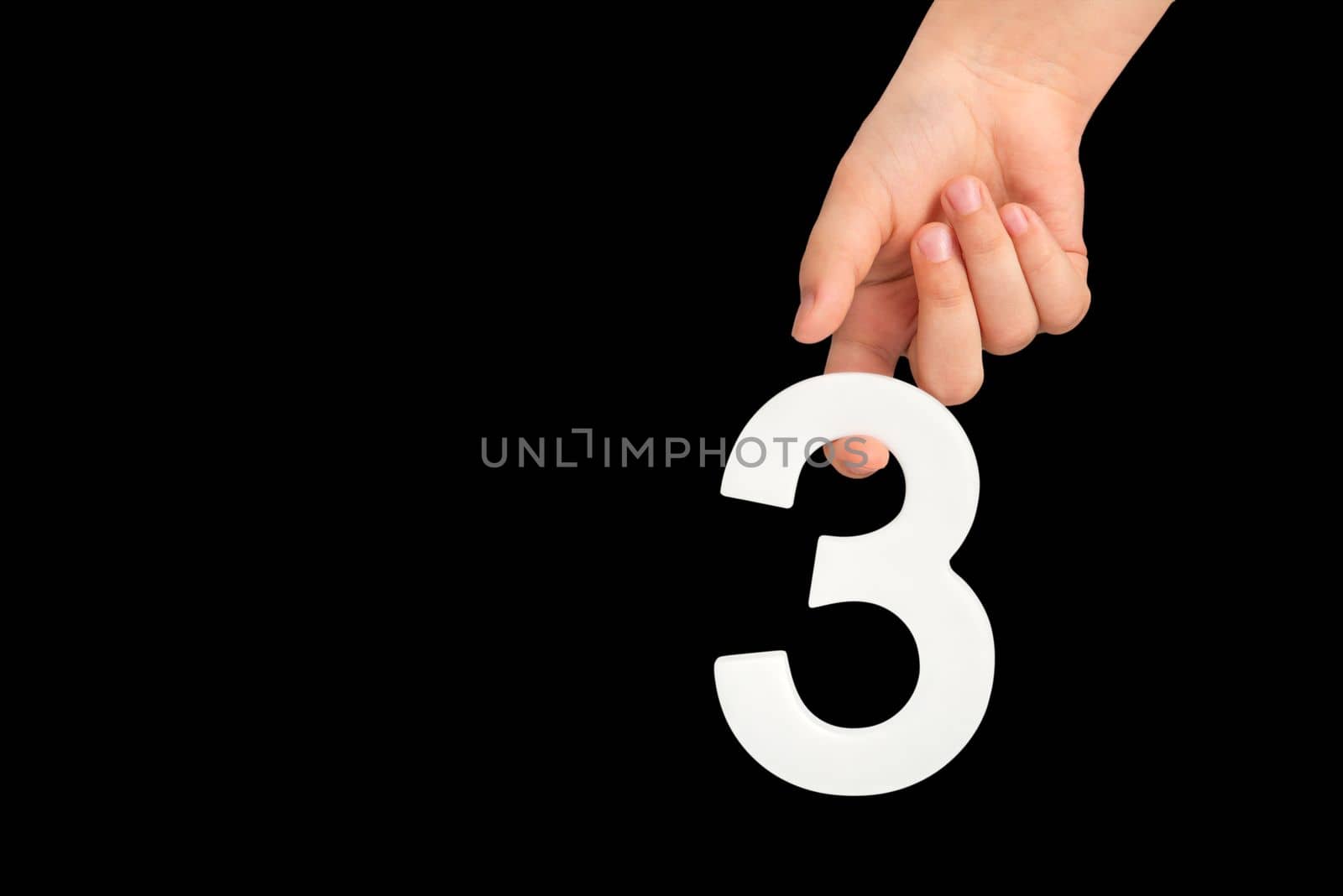 number three in hand isolated on black background. Number three in a child's hand on a black background. To be inserted into a project or design