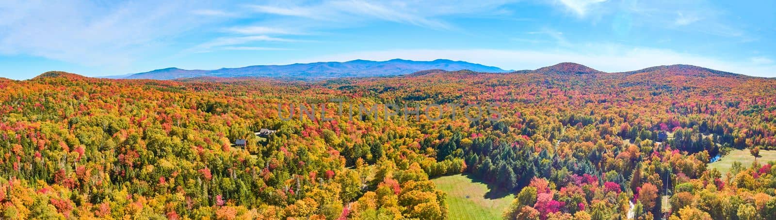 Panoramic aerial over peak fall forest mountains in Vermont with blue skies by njproductions