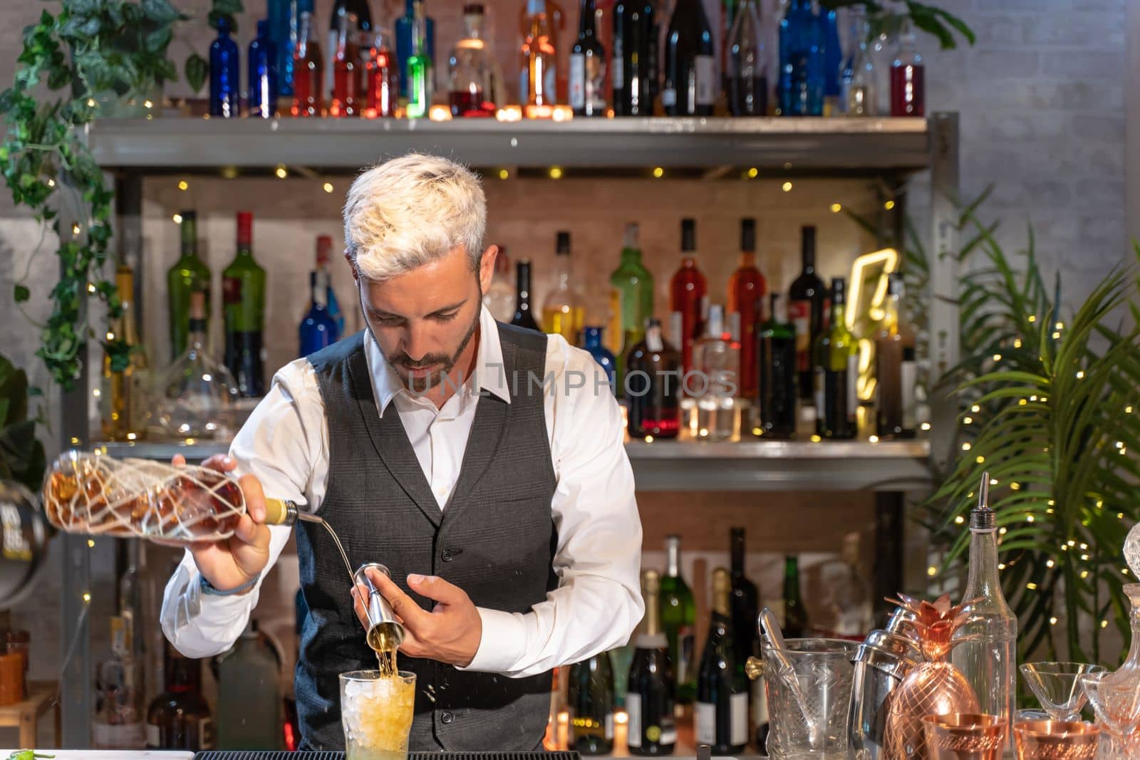 Elegant barman making cocktail Mojito in night club adding ingredients and creating expert drinks on bar counter. by PaulCarr