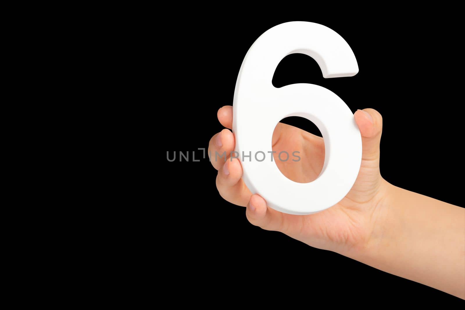 Number six in hand isolated on black background. Number six in a child's hand holding on a black background. To be inserted into a project or design