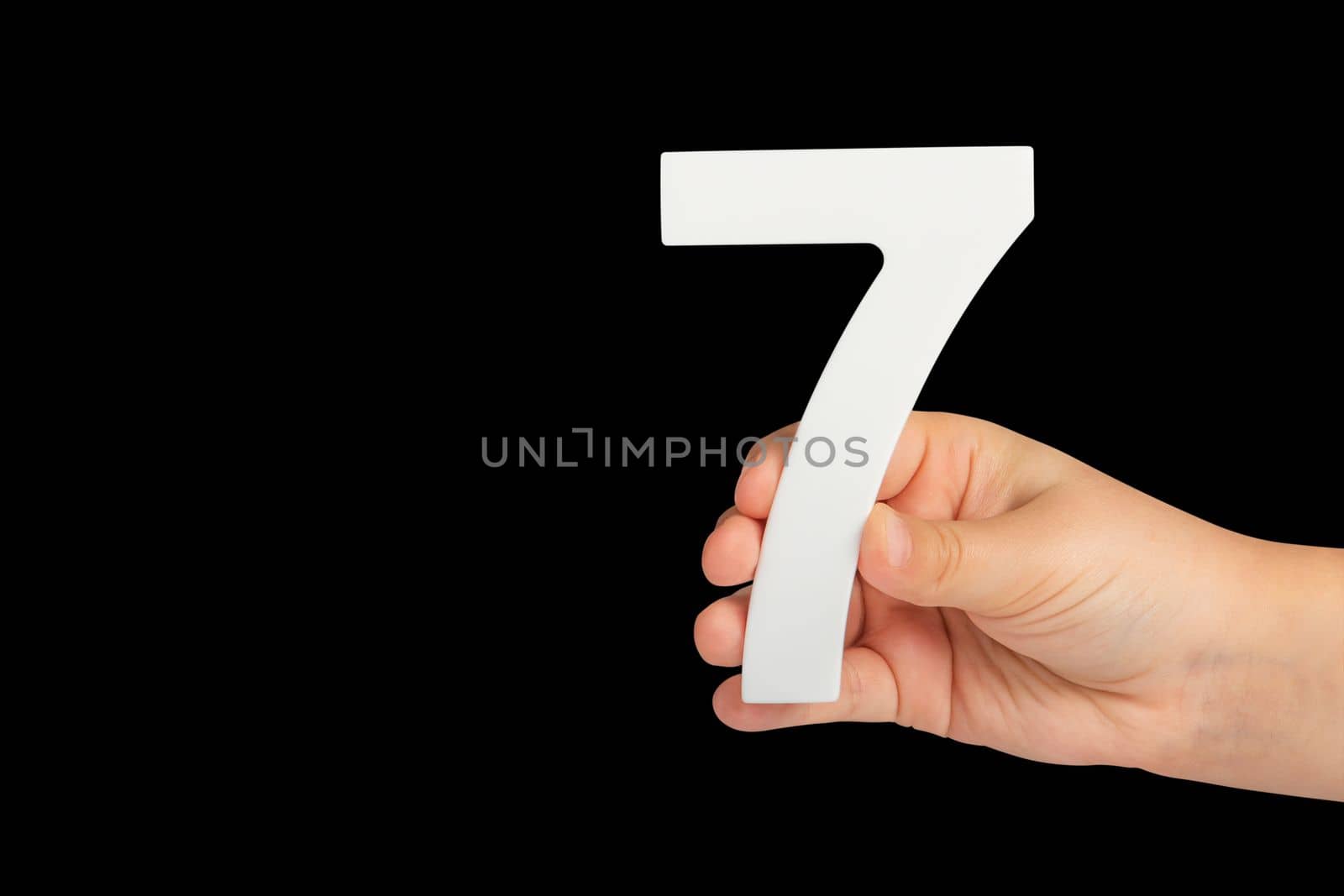 Number seven in hand isolated on black background. Number 7 in a child's hand on a black background. To be inserted into a project or design