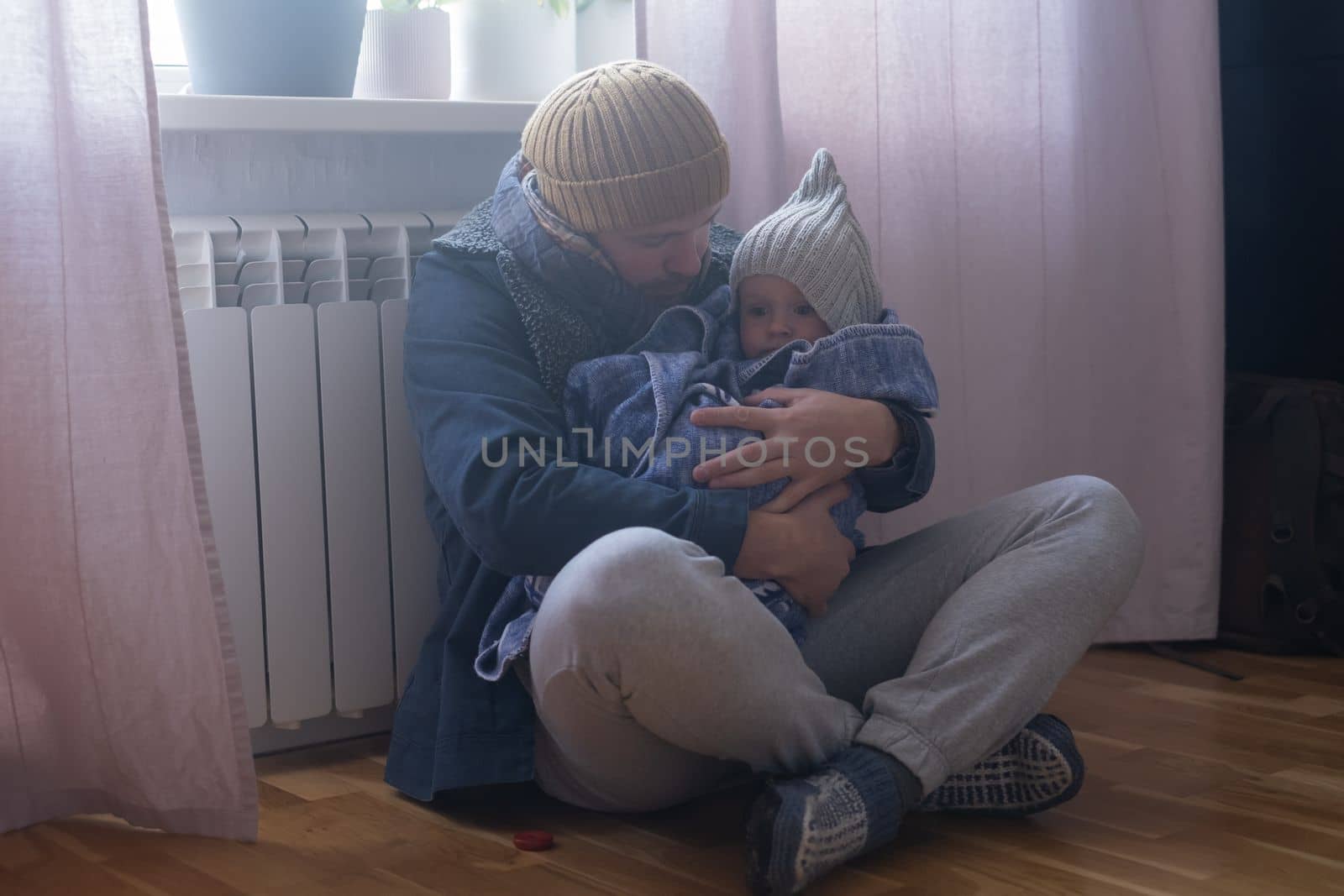 Man wearing warm clothing feeling cold checking central heating battery. Energy crisis in Europe