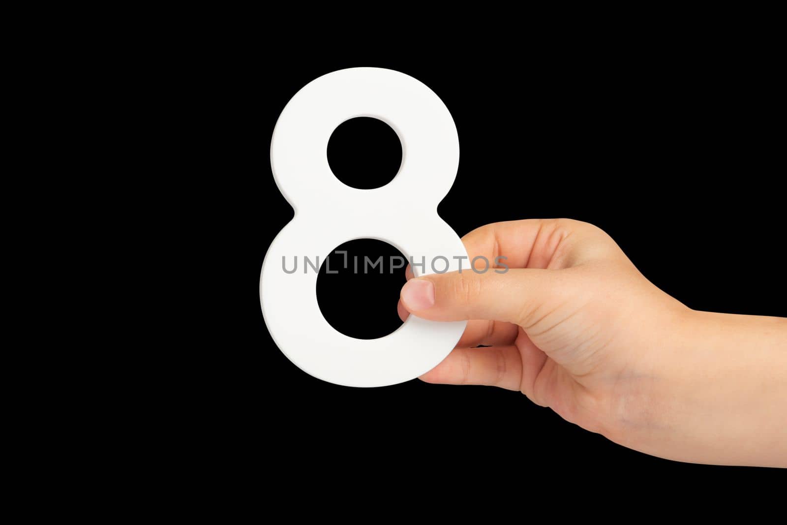 Number eight in hand isolated on black background. Number 8 in a child's hand on a black background. To be inserted into a project or design. by SERSOL