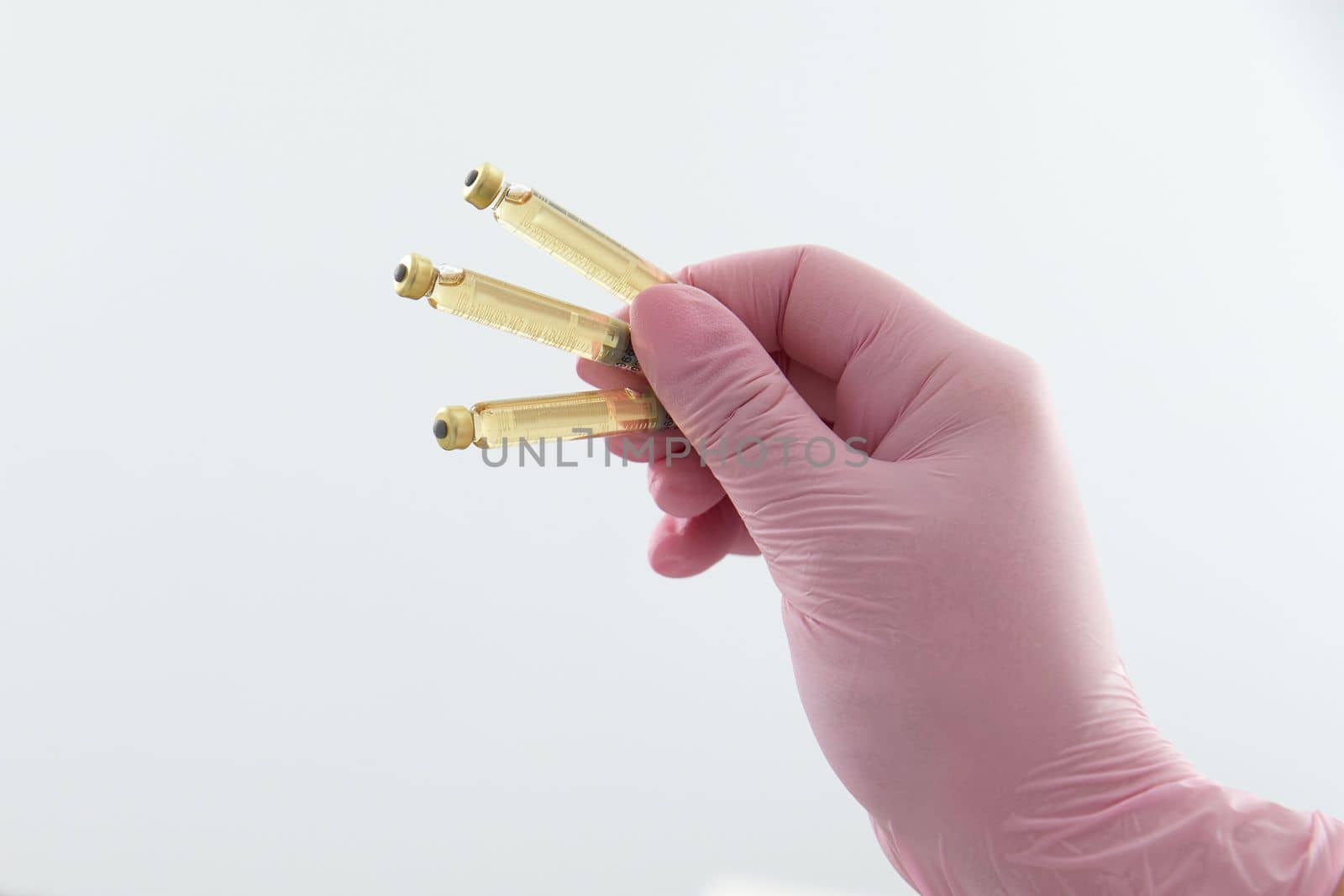 Hand wearing gloves holding three ampoules with liquid