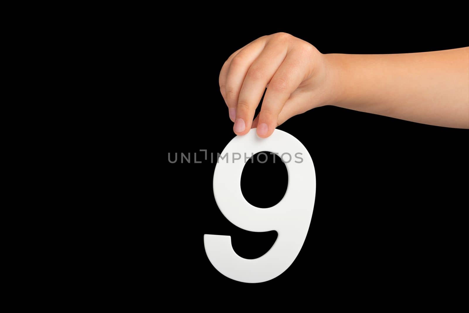 Number nine in hand isolated on black background. Number 9 in a child's hand on a black background. To be inserted into a project or design. by SERSOL