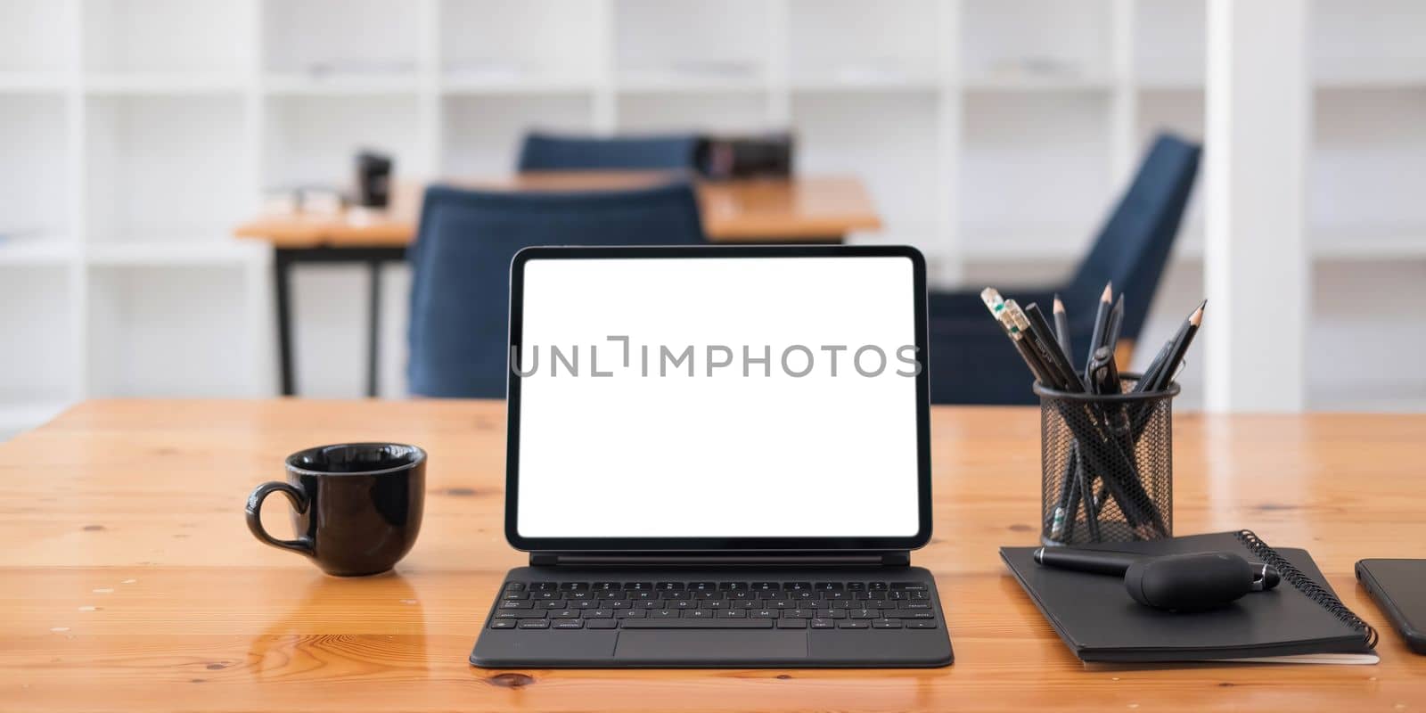 Photo of computer laptop with white blank screen putting on the modern working table with blurred comfortable office as background. Void screen for advertise concept. by wichayada