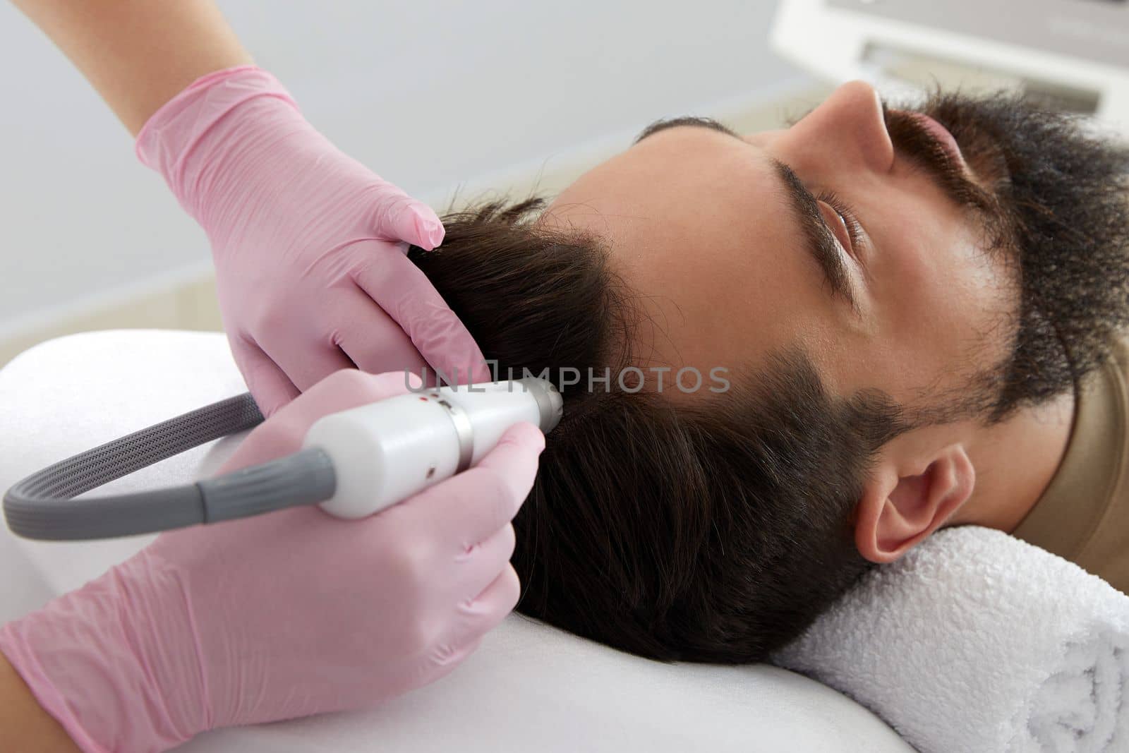 Doctor female dermatologist trichologist makes a procedure to stimulate hair growth on head to a patient man by Mariakray