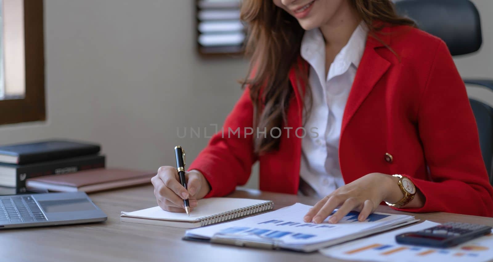 Asian Business woman using calculator and laptop for doing math finance on an office desk, tax, report, accounting, statistics, and analytical research concept..