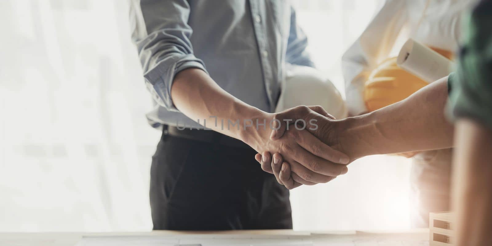 Professional Asian male engineer shaking hands with male architect after the meeting..