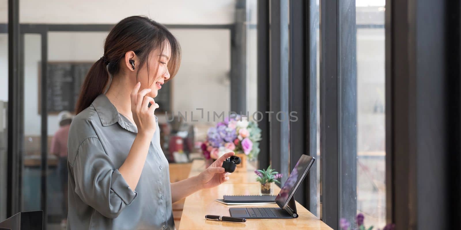 Cute asian girl listening by earphone and look at smartphone in coffee shop. by wichayada