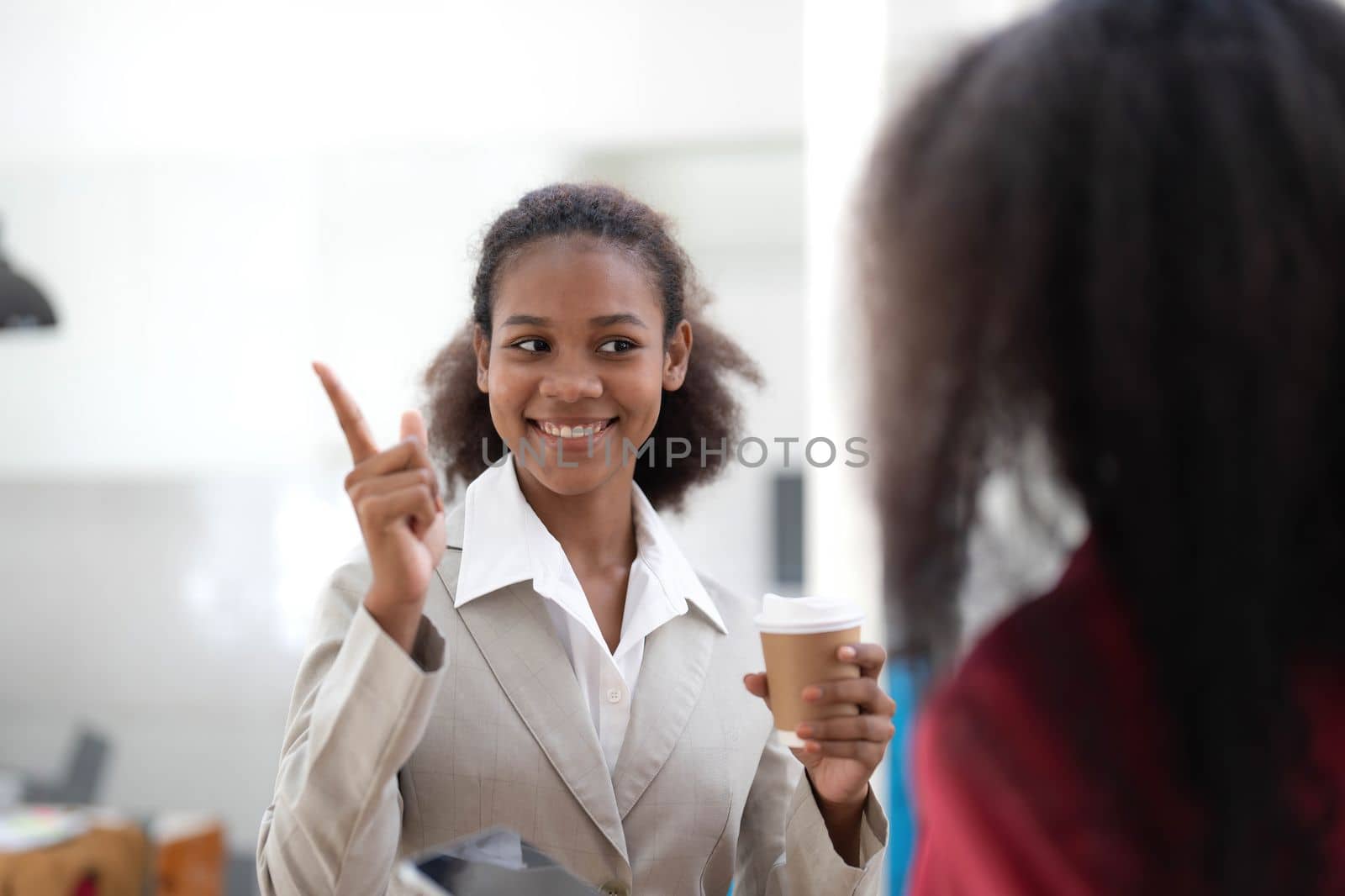 Smiling diverse colleagues businesswomen working on laptop together, looking at screen, stand at desk in office, employees discussing project strategy, sharing ideas by wichayada