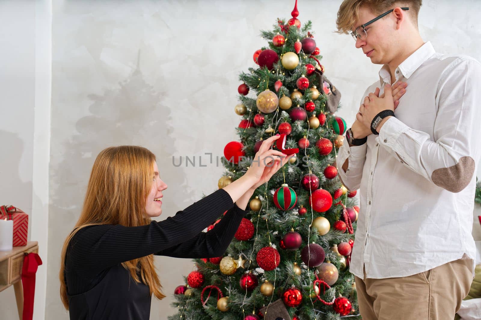 Embarrassing moment. Romantic concept. Young woman holding box with engagement ring, making marriage proposal to her boyfriend indoors, women psychology.